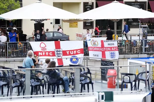 England fans on Friedrichstrasse drape flags next to the river Spree in Berlin