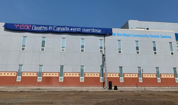 A wide shot of a building. A banner is draped over the building's roof that says 